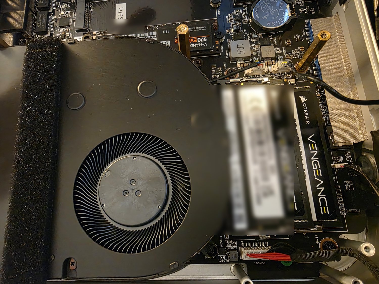 Inside the mini-PC: two Corsair Vengeance DDR5 SODIMMs beside a blower fan and an NVMe SSD, product serials blurred.